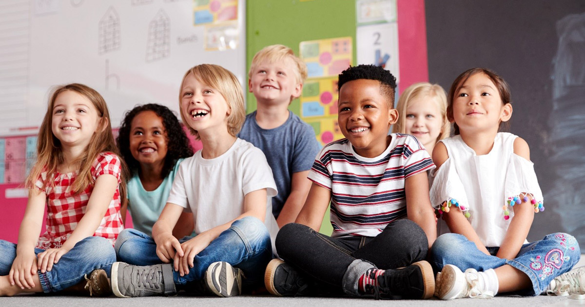 A group of children sitting on the floor in a classroom